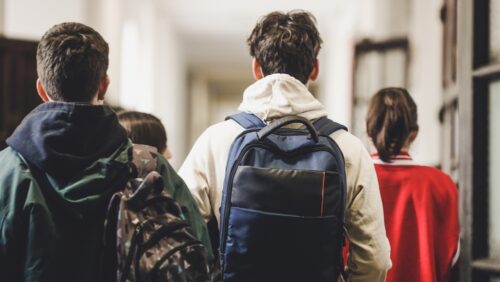 Des élèves avec leur sac à dos marchent dans le couloir d'un lycée.