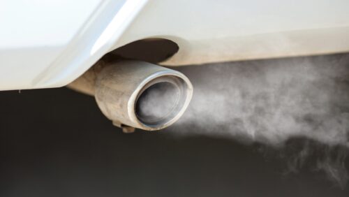 De la fumée sort d'un pot d'échappement, contribuant à la pollution de l'air.