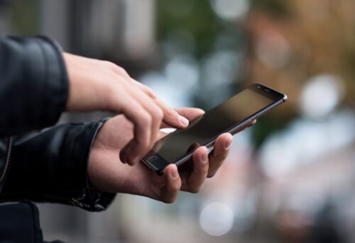 Une personne tient son téléphone mobile à la main.