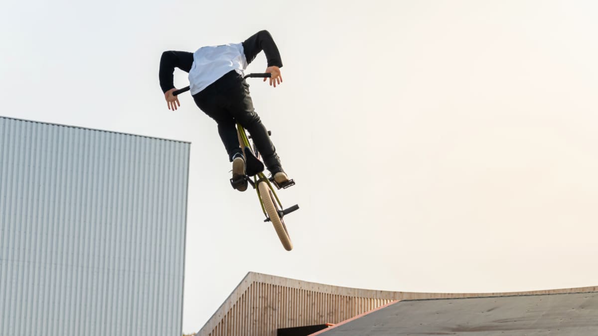 Un jeune pilote sur un vélo BMX fait des tours en l'air.