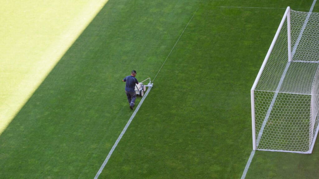 Un homme peint les lignes sur un terrain de football.